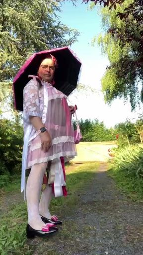 In an outfit with a pink nightgown and a sheer white dressing gown with a parasol