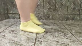 Plus size female removes stinky, dirty, neon socks off her thick feet, showing her arches, small toes and wrinkly soles in the bathroom