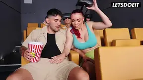 Topless redhead gives a sloppy movie theater blowjob
