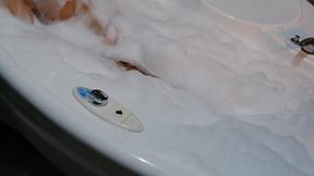 Beautiful blonde seductively teases her tits in a bubble bath