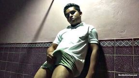 In a dark hallway, Avrool stands under a light and starts stroking that big uncut cock of his.