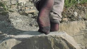 Jeans feet in black nylon socks on the seashore