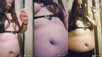 Goth girl smokes in the laundry while rubbing her belly