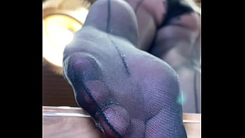 Goddess with long legs and big ass in black pantyhose on the table plays with a toe ring above your face