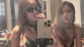Two sexy Asian girls wearing provocative uniforms, smoking in front of a mirror.