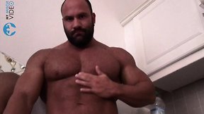 Giant bodybuilder flexing in kitchen naked