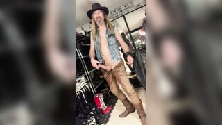 Longhairdude finishes off and smears on suntan laceup leather denim, cowboy footwear, jeans vest, cowboy hat