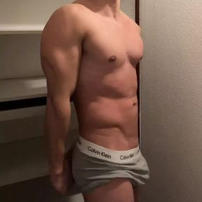 Young muscle hunk flexes his muscles in the closet