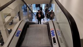 dans l escalator d un grand magasin, blouse transparente levee et seins nus ...