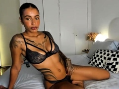 Tattooed seductress posing in sexy black lingerie on the bed