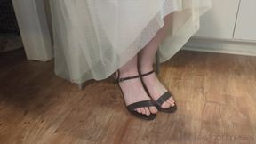 Fifi sitting in heels trying to scrunch her toes to free them from the toe strap