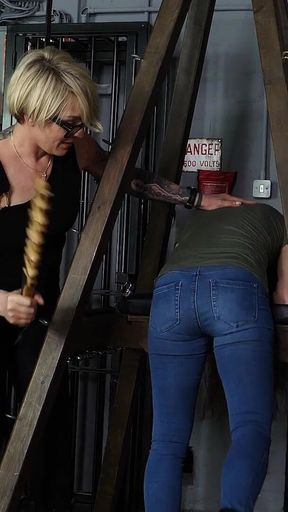 Slave Mila's Feet Dangle and Quiver as Mistress Baton Breaks in Heavy Wooden Paddle Over Her Jeans and Bare