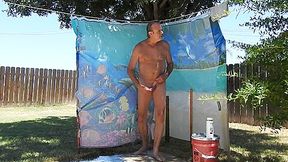 A Step daddy taking a shower, outdoors, on his patio.