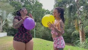 Two cute girls blowing up balloons outdoors
