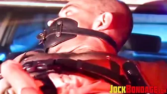 Muscular police officer tied up on car hood for outdoor bondage