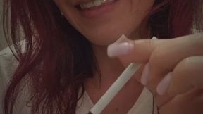 White cigarette being soften with fingers, licked and smoked