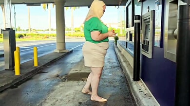 Woman in green and hijab meets stranger by silver SUV in parking lot