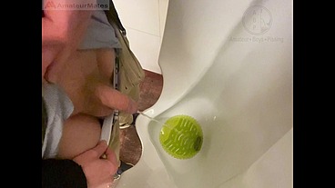 Amateur redhead guy caught pissing in a public toilet's urinal - he then quickly plays with his cock before leaving