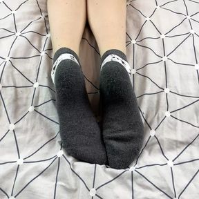 Girl with long legs caresses her feet in gray New Year socks with deer