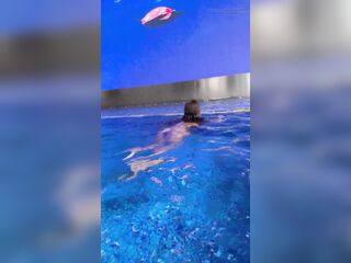 Monika Fox in Purple Bikini Swims in Pool & Positions by Window Against Background of Town