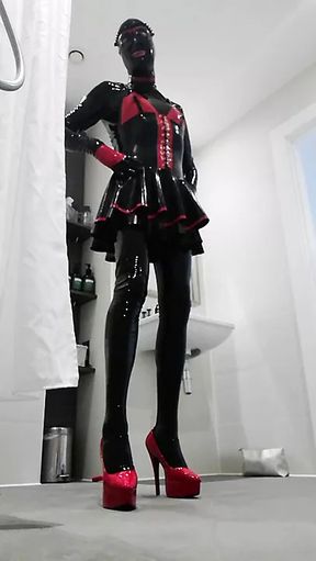 Latexdesires Alice posing in the bathroom with red stilettos and shiny black and red latex