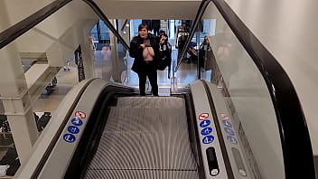 Dans l&#039_escalator d&#039_un grand magasin, blouse transparente lev&eacute_e et seins nus ...