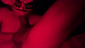 Masked in the red light sucking cock