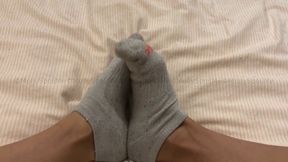 Wriggly feet in dirty white trainer socks