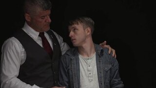 Beefy man in a suit is examining a shy blond fellow