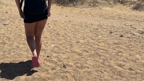 a girl in a short dress pees in the sand with foam on the beach