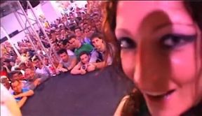 Two girls pleasing a guy in front of an audience