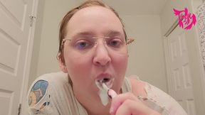 Brushing teeth and scrubbing tongue wearing glasses and torn shirt