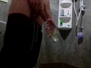 A guy in sweatpants pisses and cums in a glass for his friend, who then drinks it