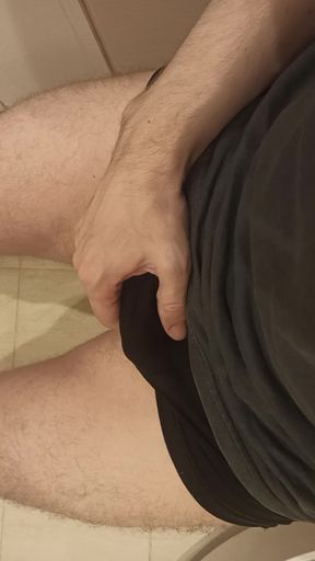 A Guy Massages His Penis While Sitting on the Toilet