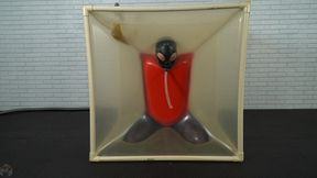 Sonya in a black latex mask gagged enclosed in a transparent cube and tied with a red latex top