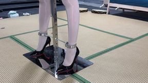 Asian woman bound by metal braces, high heels, shackles, handcuffs, experiencing vibrating orgasm.