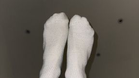 Male athlete takes off white socks after a long day and a good workout.