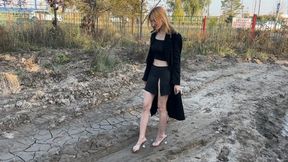 girl in mules in high heels walks through the mud and gets her feet dirty