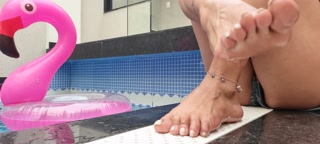 PLAYING WITH THE FEET ON THE SIDE OF THE POOL WITH THE BUOY