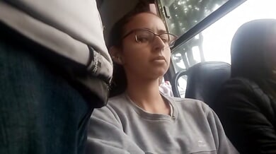 Young Brazilian woman with glasses rests on a bus while being subtly observed