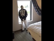 skeleton mask in pantyhose and jeans at hotel window