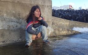 A Cute Expressiagirl in a Tracksuit Sat Down to Pee Near the Ocean